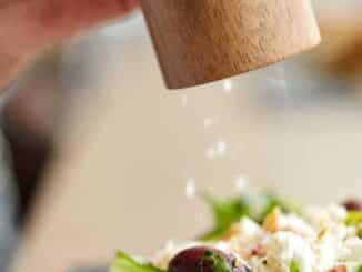 hand shaking salt onto a salad