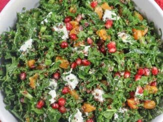 Colorful kale salad with oranges, goat cheese, pomegranate in a white bowl on a red placemat