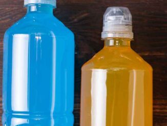 two bottles of sports drinks on a dark surface