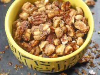 Low sodium caramelized nuts with brown sugar and spice in a small yellow bowl on a black slate surface
