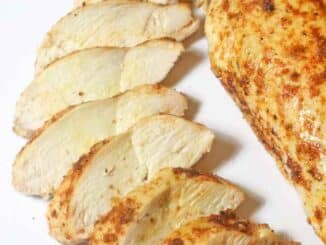 sliced chicken breast and a whole chicken breast on a white plate
