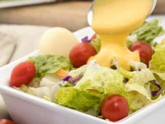 salad in a bowl, dressing being poured