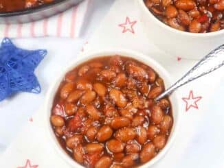 baked beans in a small white bowl with a spoon on a red and white kitchen towel
