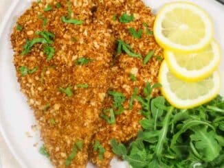 breaded chicken cutlets on plate with arugula and lemon slices